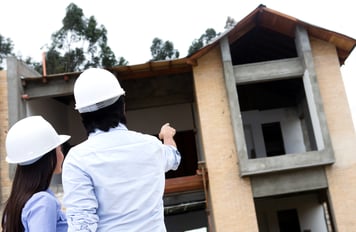 Architects at a construction site pointing at a house